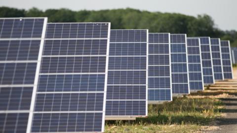 A general view of a solar farm. The solar panels are tilted at a 45 degree angle toward the sky. 