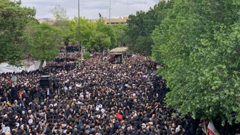 Thousands of mourners gather in the Iranian city of Tabriz as the late president's casket is driven in a procession.