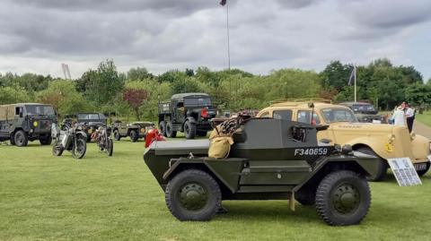 A selection of military vehicles at a previous Armed Forces Weekend at the National Memorial Arboretum. Different types of vehicles are in the picture, including two motorcycles. 