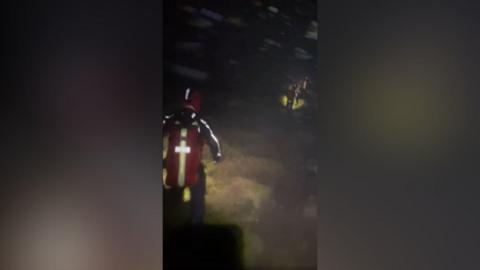 Headcam footage from one of the rescue teams, showing members walking in line through darkness, high winds and snow