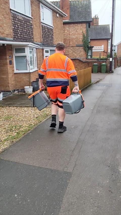 A worker delivers food waste bins
