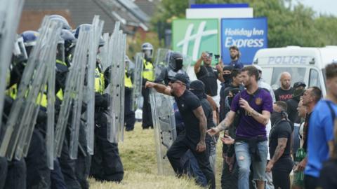 Protestors face police officers with riot shields