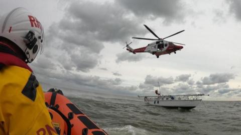 A paramedic is lowered from a helicopter onto the stricken yacht at sea