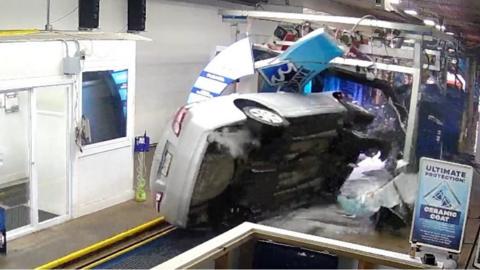 Car resting on one side inside car wash