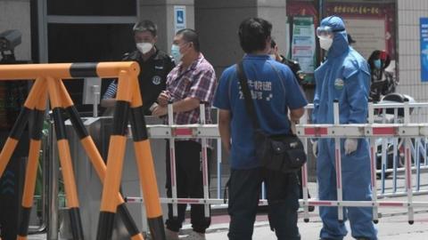 Security guards at a residential area under restrictions near Yuquan East Market in Beijing