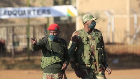 Members of the Zimbabwe National Army (ZNA) stand guard at a check point in the central business district in Harare