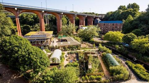 Aerial shot of farm and in the background is a bridge. 