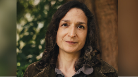 Headshot of Angela Tomaski smiling outside in front of a tree.