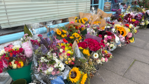 Dozens of bouquets left on a pavement outside a pet shop in Wiltshire.
