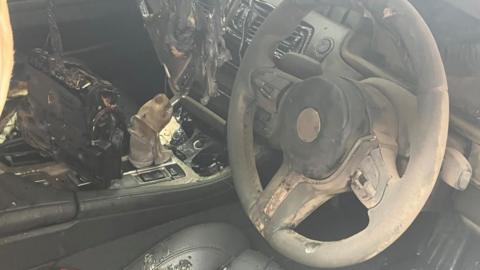 The car's interior shown with severe fire damage.