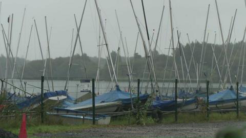 Dinghies behind a fence by the lake's activity centre