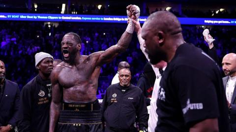 Deontay Wilder celebrates as Derek Chisora looks on
