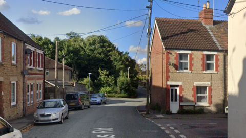 Woodlands Road in Chippenham. It is a residential street with terraced houses. Cars align the image on the left.