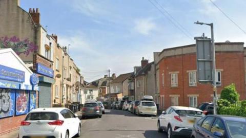 A Google Maps screengrab of Oxford Place in Easton, Bristol, a narrow residential street lined with parked cars with a garage on the corner.
