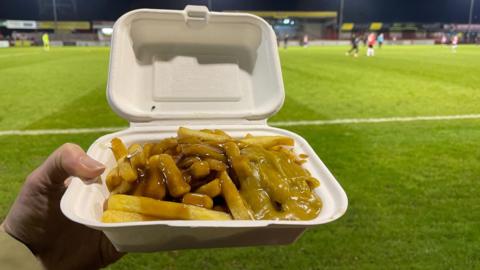 Curry and chips being eaten pitchside at a football match