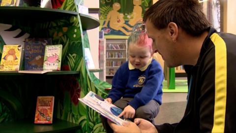 Father reading to daughter