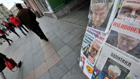 People pass by a kiosk in the main street of Bosnia and Herzegovina's capital Sarajevo, with all newspapers' frontpages displaying former Bosnian Serb leader Radovan Karadzic on March 21, 2019
