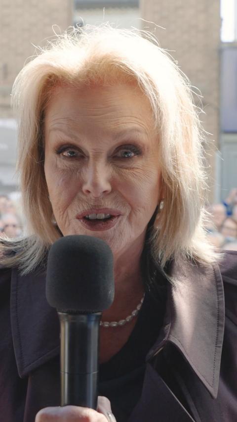 Joanna Lumley stood in front of a camera with a black microphone wishes Sir David Attenborough a happy birthday
