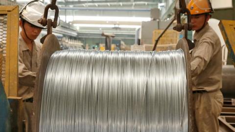 Workers handling steel cables at a steel factory in China.