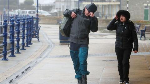 Pedestrians struggle to walk in the wind on the promenade in Porthcawl, south Wales