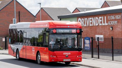 A red NCT bus outside the school in Rivendell