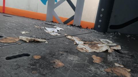 Debris on the black play equipment from the attempted arson. There are burn marks with pieces of burnt paper scattered around. 