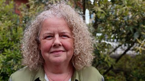 Clare Down, one of the women who was given a fast MRI scan during a trial in North Bristol which picked up a cancerous tumour. She is wearing a green blouse and has blonde hair.