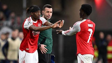 Noni Madueke of Arsenal reacts with Bukayo Saka as he enters the pitch as a substitute during the UEFA Champions League 2025/26 Round of 16 First Leg match between Bayer 04 Leverkusen and Arsenal FC.