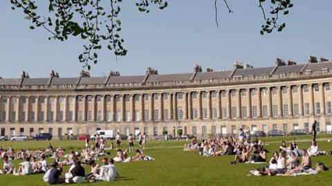 People sit in park in Bath enjoying sun