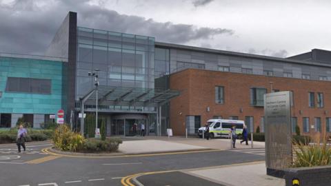 The Northern Centre for Cancer Care at the Freeman Hospital. The building has a red-brick section to the right. The main entrance is in the middle and is made predominantly from glass.