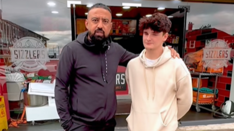 Arfan and Tyler stand together outside Sizzlers. Arfan has his arm around Tyler. Tyler has short brown hair and and Arfan is wearing a black top.