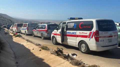 Ambulances line up near a mass grave