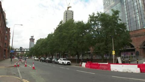 Cars parked near Deansgate Locks with a sign on a lamp-post appealing for information on the crash