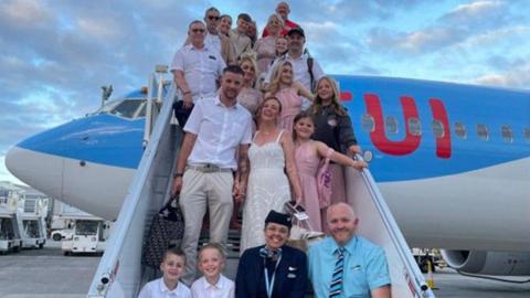 The wedding party on the steps of the aeroplane with a members of TUI crew