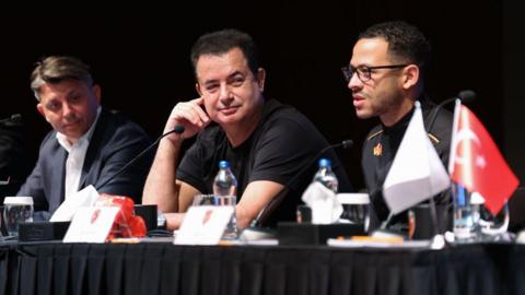 Liam Rosenior speaks during a Hull City press conference in Antalya, Turkey in March 2024. Hull City's owner Acun Ilicali and vice president Tan Kesler are sat alongside him. 