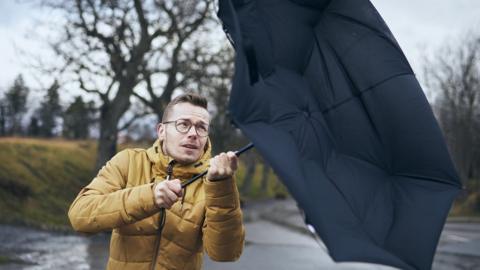 Man holding broken umbrella in strong wind (stock image)