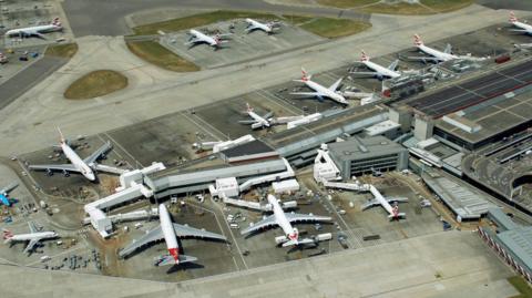 A bird's eye view of Heathrow Airport, with 12 planes waiting outside terminals