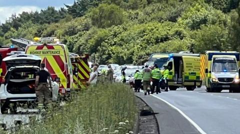 Emergency services vehicles and personnel on the A34 dual carriageway, with stopped cars in the background