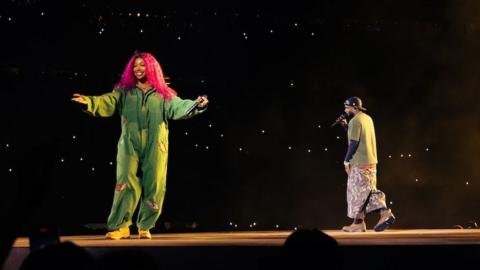 SZA appears in a jumpsuit alongside Kendrick Lamar in a green top and trousers