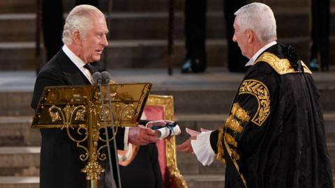 King Charles III presents a copy of his address to Speaker of the House of Commons Sir Lindsay Hoyle at Westminster Hall, London