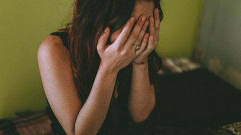 A woman sits with her head in her hands