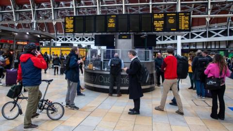 File image showing commuters looking up at arrival boards in Paddington train station