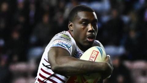Sam Eseh playing for Wigan, carrying the rugby ball in his right arm