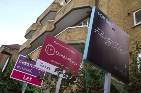Two colourful 'to let' and one colourful 'for sale' boards outside a block of London flats