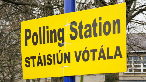 A yellow polling station sign, in English and Irish, on a blue pole