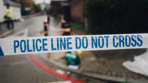 Police tape in a street covering a crime scene