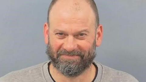 Barnaby Money with a grey beard and a grey sweat-shirt in a custody image.