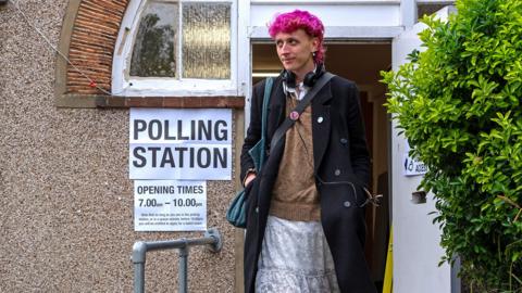 A person walks out of a voting station next to a sign reading 'polling station' in Lewisham on Thursday