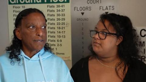 Two women stood inside a lift looking serious