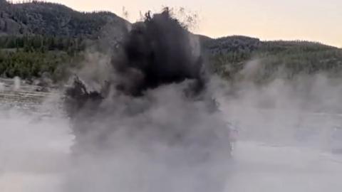 A dark mass of murky water erupts into the sky from the Black Diamond Pool in Yellowstone Park.